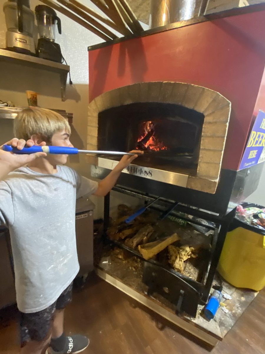 Matthew Mans loads a pizza into the wood burning oven at Halagains. 